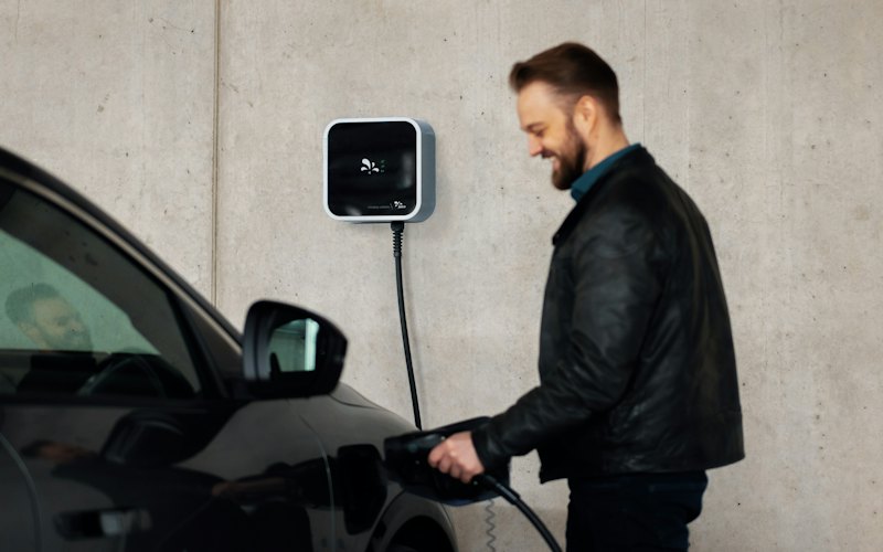 Mann lädt sein Elektroauto an einer Wallbox in der Garage
