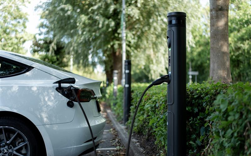 Elektroauto lädt an einer Ladesäule auf einem begrünten Parkplatz